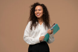 Fotografia de jovem mulher de cabelos segurando pastas de trabalho