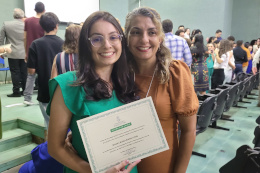 Filha segura diploma magna cum laude, ao lado da mãe, em cerimônia de entrega de distinção acadêmica no centro de ciências da UFC